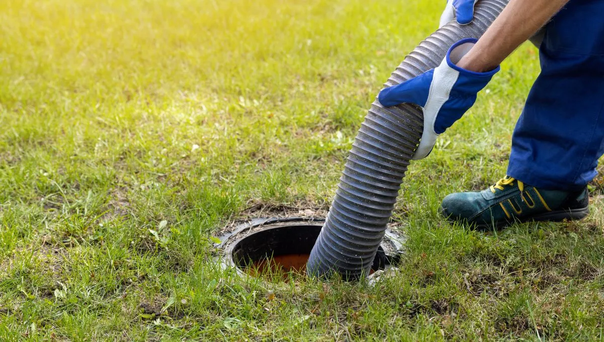  Person performing septic tank maintenance with a hose.