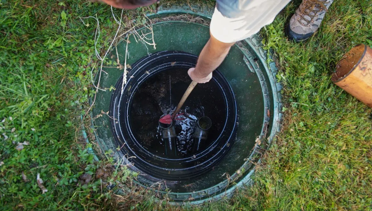 Person inspecting a septic tank with tools.